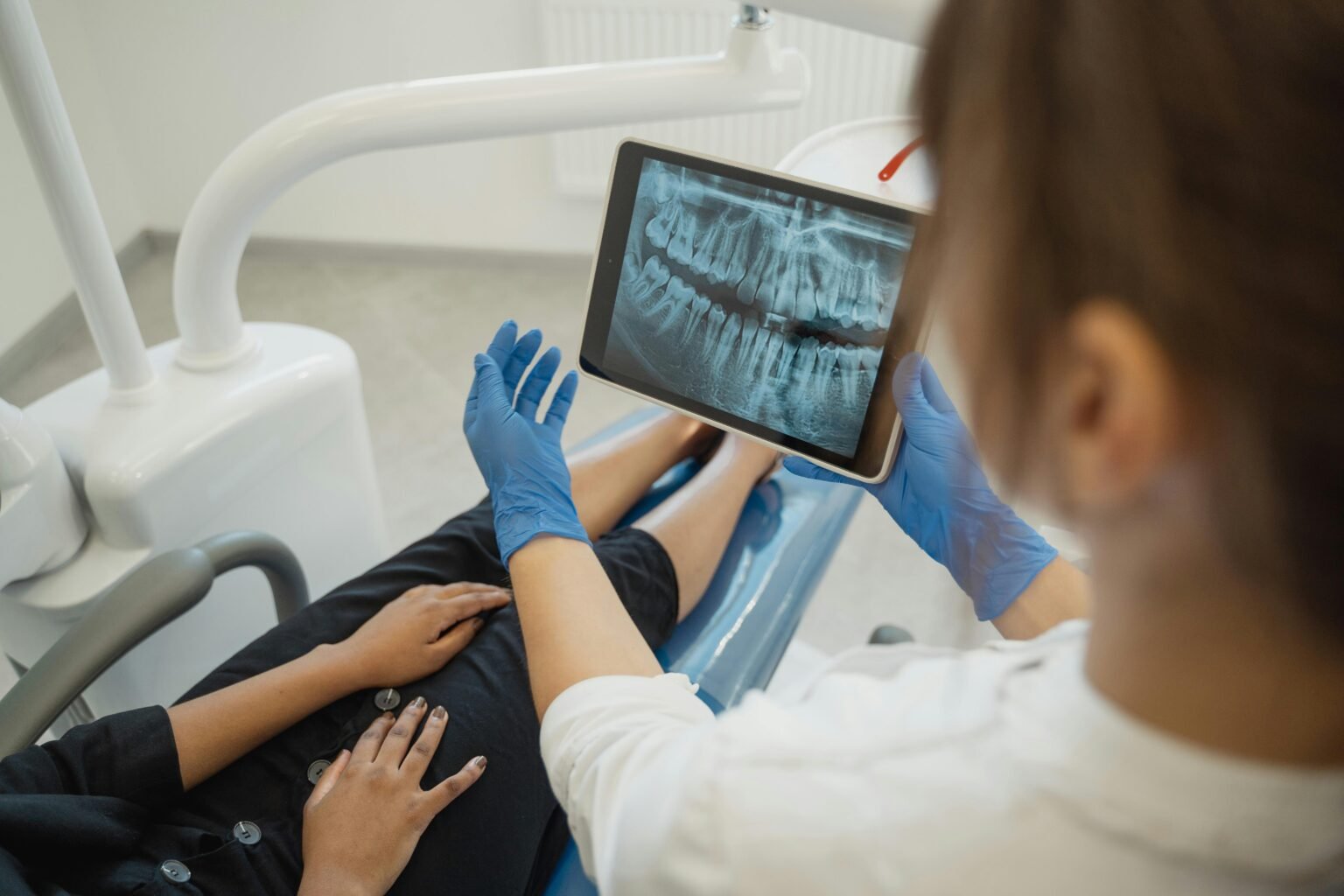 Acasa A dentist showing a dental x-ray on a tablet to a patient in a clinic.